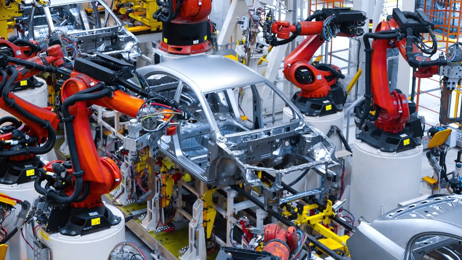 Linha de produção industrial moderna com robôs colaborativos e telas digitais exibindo dados em tempo real, ilustrando a Indústria 4.0 em operação.